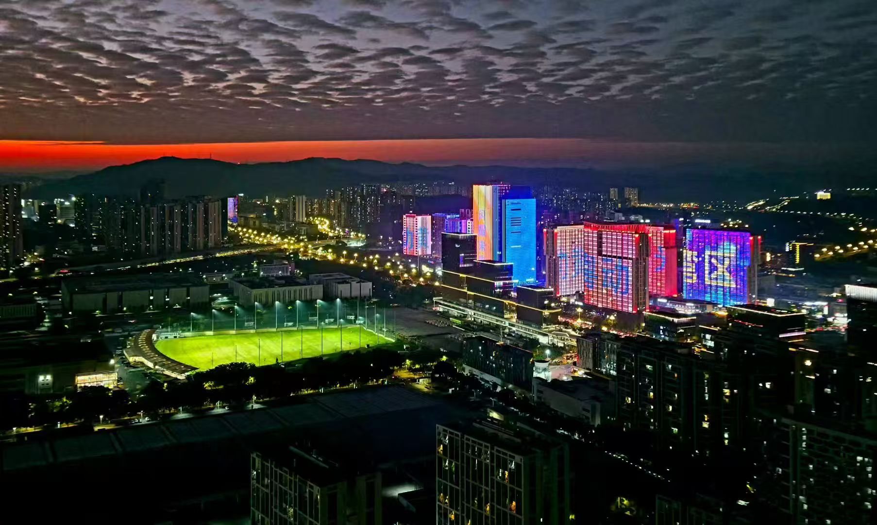 131高尔夫灯光练习场夜景航拍，城市天际线下的绿色球场